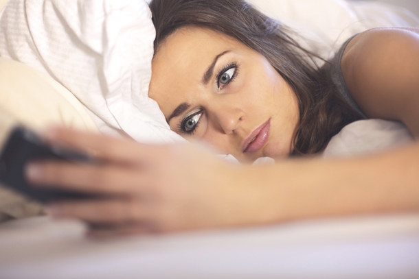 Woman on Bed Reading a booty call Text Message