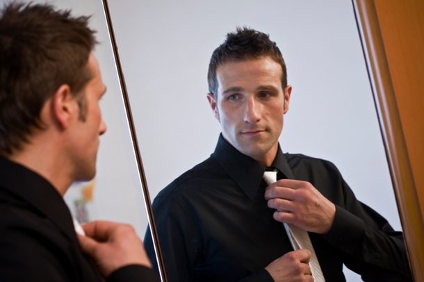 Man Adjusting Tie in Mirror
